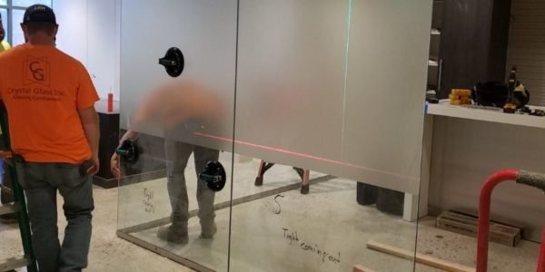 workers installing glass wall in building
