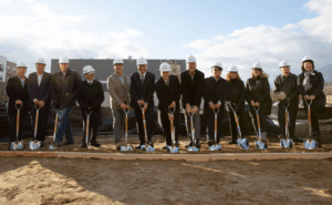 People digging with ceremonial shovels while wearing hardhats